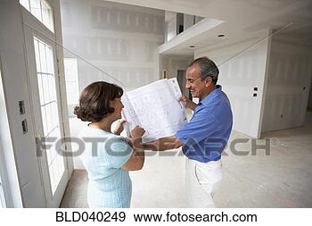 Stock Photograph - senior hispanic 
couple looking 
at blueprints 
in new house. 
fotosearch - search 
stock photos, 
pictures, images, 
and photo clipart
