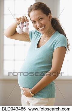Stock Photo - pregnant hispanic 
woman holding 
baby shoes. fotosearch 
- search stock 
photos, pictures, 
images, and photo 
clipart