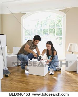 Stock Photo - multi-ethnic couple 
sealing moving 
box. fotosearch 
- search stock 
photos, pictures, 
images, and photo 
clipart