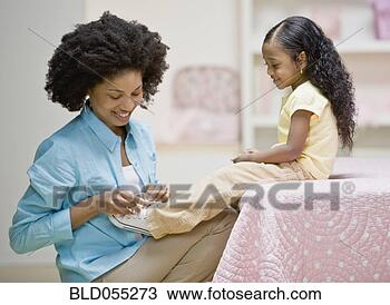 Stock Photo - african mother 
tying daughter’s 
shoe. fotosearch 
- search stock 
photos, pictures, 
images, and photo 
clipart