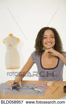 Picture - african woman 
at table with 
fashion design 
tools. fotosearch 
- search stock 
photos, pictures, 
images, and photo 
clipart
