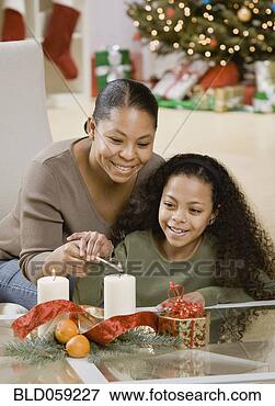 Picture - mixed race mother 
and daughter lighting 
christmas candles. 
fotosearch - search 
stock photos, 
pictures, images, 
and photo clipart