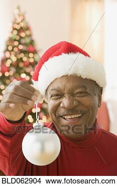 Stock Photo - african man wearing 
santa hat and 
holding christmas 
ornament. fotosearch 
- search stock 
photos, pictures, 
images, and photo 
clipart