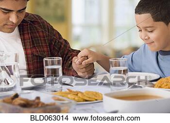 Stock Photo - hispanic father 
and son praying 
at dinner table. 
fotosearch - search 
stock photos, 
pictures, images, 
and photo clipart