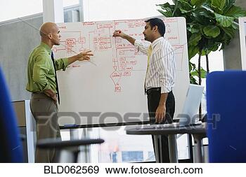 Stock Photograph - multi-ethnic businessmen 
writing on whiteboard 
in office. fotosearch 
- search stock 
photos, pictures, 
images, and photo 
clipart