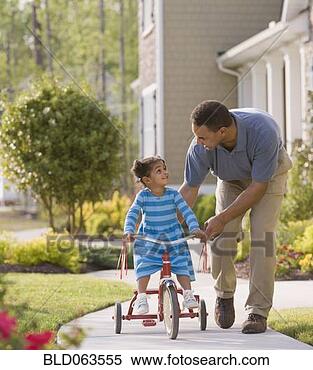 Stock Image - african father 
teaching daughter 
to ride tricycle. 
fotosearch - search 
stock photos, 
pictures, images, 
and photo clipart