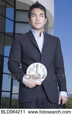 Stock Photography - asian businessman 
holding clock 
outdoors. fotosearch 
- search stock 
photos, pictures, 
images, and photo 
clipart
