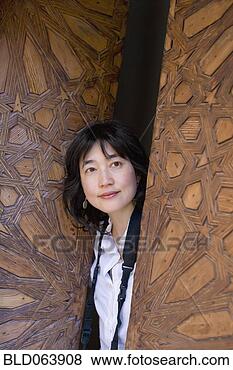 Stock Photo - asian woman peering 
out of ornate 
wooden door. fotosearch 
- search stock 
photos, pictures, 
images, and photo 
clipart