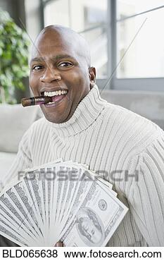 Stock Photo - african man smoking 
cigar and holding 
100 dollar bills. 
fotosearch - search 
stock photos, 
pictures, images, 
and photo clipart