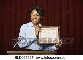 Picture - mixed race businesswoman 
speaking at podium 
with certificate. 
fotosearch - search 
stock photos, 
pictures, images, 
and photo clipart