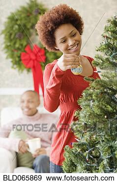 Stock Photograph - mixed race woman 
placing ornament 
on christmas tree. 
fotosearch - search 
stock photos, 
pictures, images, 
and photo clipart