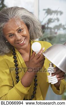 Stock Photo - african woman 
changing lightbulb 
at home. fotosearch 
- search stock 
photos, pictures, 
images, and photo 
clipart