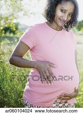 Stock Photo - young pregnant 
woman standing 
outdoors holding 
her stomach. fotosearch 
- search stock 
photos, pictures, 
images, and photo 
clipart