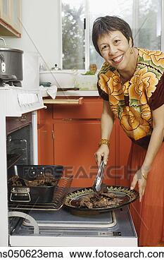 Stock Photography - woman putting 
cooked meat onto 
a plate. fotosearch 
- search stock 
photos, pictures, 
images, and photo 
clipart