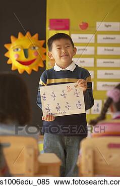 Stock Image - boy standing in 
front of a class 
holding a sheet 
of paper. fotosearch 
- search stock 
photos, pictures, 
images, and photo 
clipart