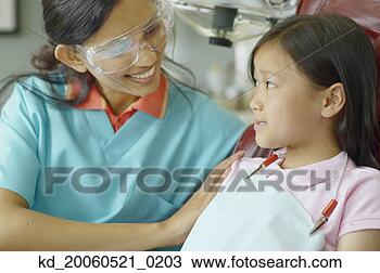 Stock Photo - indian female 
dental assistant 
smiling at young 
asian female patient. 
fotosearch - search 
stock photos, 
pictures, images, 
and photo clipart
