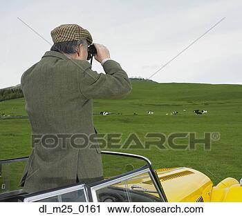 Stock Photography - man standing in 
car looking at 
countryside with 
binoculars. fotosearch 
- search stock 
photos, pictures, 
images, and photo 
clipart