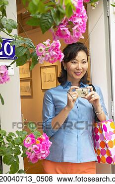Stock Photo - mid adult woman 
holding a camera. 
fotosearch - search 
stock photos, 
pictures, images, 
and photo clipart