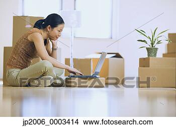 Stock Photo - asian woman using 
laptop in new 
house with boxes. 
fotosearch - search 
stock photos, 
pictures, images, 
and photo clipart