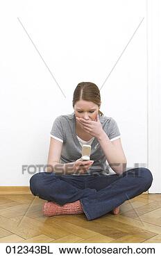 Stock Photo - young woman shocked 
by news on her 
mobile phone. 
fotosearch - search 
stock photos, 
pictures, images, 
and photo clipart