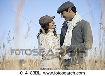 Stock Photo - young couple smiling 
at each other 
in autumnal field. 
fotosearch - search 
stock photos, 
pictures, images, 
and photo clipart