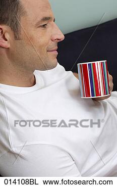 Stock Photo - portrait of young 
man relaxing with 
coffee cup on 
sofa. fotosearch 
- search stock 
photos, pictures, 
images, and photo 
clipart