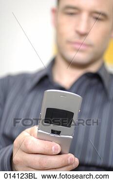 Stock Photo - young man checking 
his mobile phone 
for text messages. 
fotosearch - search 
stock photos, 
pictures, images, 
and photo clipart