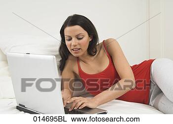 Stock Photo - young woman lying 
on bed with laptop 
computer. fotosearch 
- search stock 
photos, pictures, 
images, and photo 
clipart