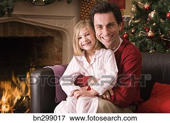 Picture - father and daughter 
on couch with 
christmas tree 
and fireplace. 
fotosearch - search 
stock photos, 
pictures, images, 
and photo clipart
