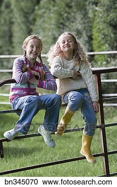 Stock Photography - sisters sitting 
on gate of fence. 
fotosearch - search 
stock photos, 
pictures, images, 
and photo clipart