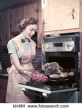 Stock Photo - 1950s housewife 
smiling wear apron 
take roast with 
potatoes out of. 
fotosearch - search 
stock photos, 
pictures, images, 
and photo clipart