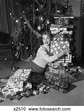 Stock Photography - 1950s woman sitting 
on floor in front 
of xmas tree holding 
packages. fotosearch 
- search stock 
photos, pictures, 
images, and photo 
clipart