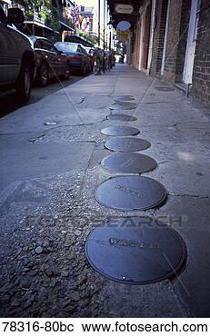 Stock Photography - water line plate 
covers on worn 
city sidewalk, 
 new orleans. 
fotosearch - search 
stock photos, 
pictures, images, 
and photo clipart