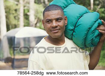 Stock Photo - man carrying sleeping 
bag at campsite. 
fotosearch - search 
stock photos, 
pictures, images, 
and photo clipart