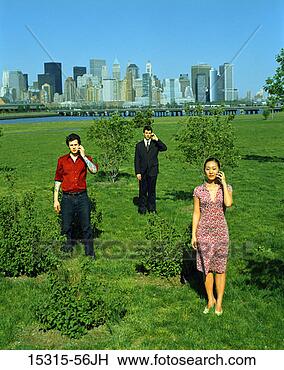 Stock Photo - three young adults 
on cellphones 
standing on grass 
at liberty state. 
fotosearch - search 
stock photos, 
pictures, images, 
and photo clipart