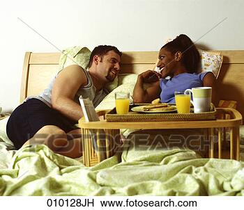 Stock Photo - young interracial 
couple having 
breakfast in bed. 
fotosearch - search 
stock photos, 
pictures, images, 
and photo clipart