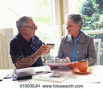 Stock Photo - senior couple 
sitting at a table 
going over finances. 
fotosearch - search 
stock photos, 
pictures, images, 
and photo clipart