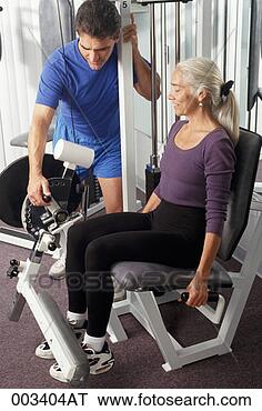 Stock Photo - personal trainer 
helping senior 
woman workout 
on leg extension. 
fotosearch - search 
stock photos, 
pictures, images, 
and photo clipart