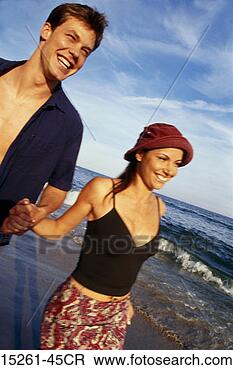 Stock Photo - a young adult 
caucasian straight 
couple walking 
on a beach holding. 
fotosearch - search 
stock photos, 
pictures, images, 
and photo clipart