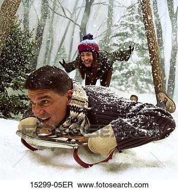 Stock Photo - couple sledding 
by snowy woods, 
on winter day. 
fotosearch - search 
stock photos, 
pictures, images, 
and photo clipart