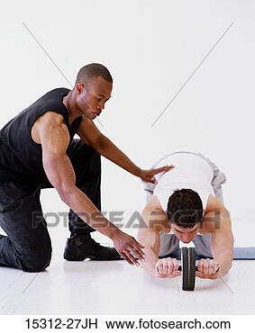 Stock Photo - fitness trainer 
with client using 
exercise wheel. 
fotosearch - search 
stock photos, 
pictures, images, 
and photo clipart