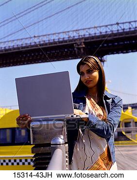 Stock Photo - young woman using 
laptop computer 
resting on railing, 
 with manhattan. 
fotosearch - search 
stock photos, 
pictures, images, 
and photo clipart