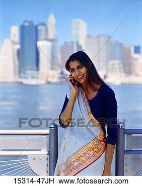 Stock Photo - young woman wearing 
sari,  talking 
on cellphone, 
 standing by railing. 
fotosearch - search 
stock photos, 
pictures, images, 
and photo clipart