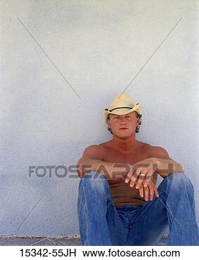 Stock Photo - shirtless man 
in cowboy hat 
and jeans, sitting 
by blue wall. 
fotosearch - search 
stock photos, 
pictures, images, 
and photo clipart