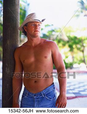 Stock Photo - shirtless man 
in cowboy hat 
and jeans, leaning 
against post, 
belize. fotosearch 
- search stock 
photos, pictures, 
images, and photo 
clipart