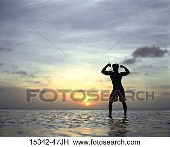 Stock Photo - silhouette of 
man flexing muscles, 
standing in ocean, 
belize. fotosearch 
- search stock 
photos, pictures, 
images, and photo 
clipart