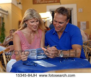 Stock Photo - prime couple reading 
travel brochure, 
 sitting at outdoor 
cafe. fotosearch 
- search stock 
photos, pictures, 
images, and photo 
clipart