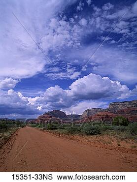 Stock Photo - blue sky and clouds 
above dirt road 
through rugged 
landscape. fotosearch 
- search stock 
photos, pictures, 
images, and photo 
clipart