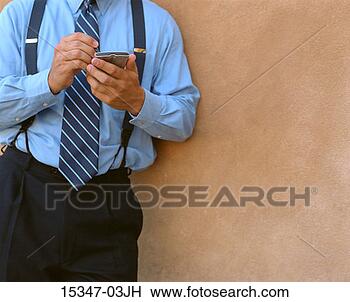 Stock Photo - mid torso view 
of prime businessman 
using pda and 
standing by wall. 
fotosearch - search 
stock photos, 
pictures, images, 
and photo clipart