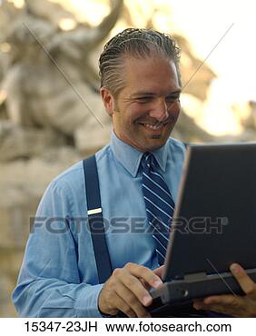 Stock Photo - prime businessman 
using laptop computer, 
 by fountain, 
 piazza. fotosearch 
- search stock 
photos, pictures, 
images, and photo 
clipart